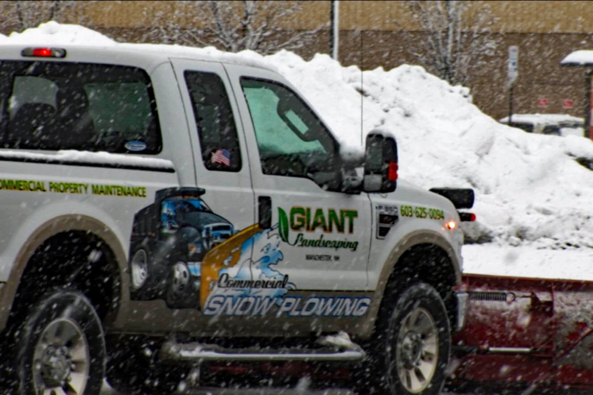 Side view of Giant Landscaping snow plow truck with the words Commercial Property Maintenance and their logo