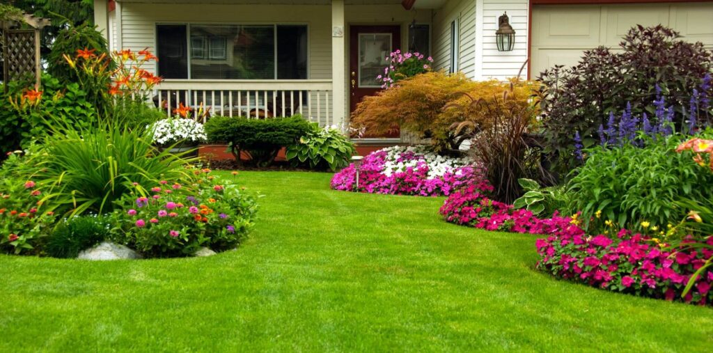 quaint white home with flowers, bushing and lush green lawn